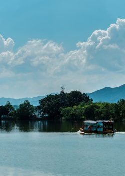 A boat floats on a calm lake under a cloudy sky.
