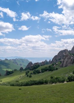 Green hills and rocky mountains under a blue sky.
