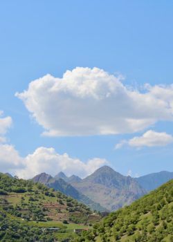 Mountains and puffy clouds fill the scenic landscape.