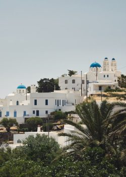 Whitewashed buildings with blue domes dot the hillside.