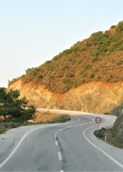 a curved road with a mountain in the background
