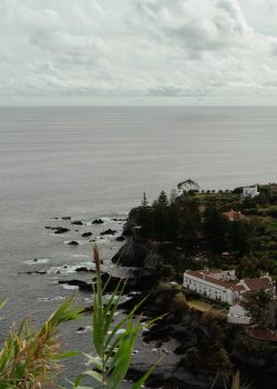 a large body of water next to a lush green hillside